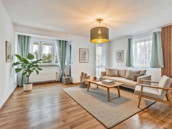 Heller Wohn- und Essbereich mit Holzboden, Sofa und großen Fenstern